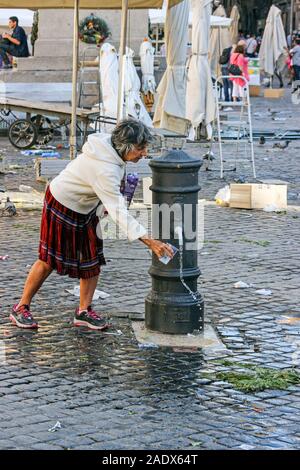 Capelli grigi lady ottenere acqua potabile da bere nasone fontana a Campo de' Fiori piazza del mercato di Roma, Italia Foto Stock