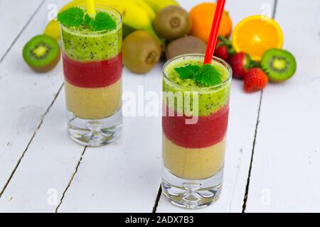 Due bicchieri con cocktail di frutta su un bianco tavolo in legno da schede con frutta in background Foto Stock