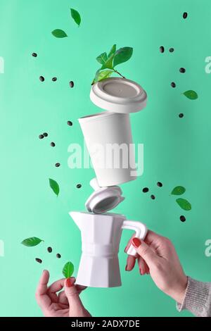 Equilibratura di rifiuti zero piramide di caffè in mani femminili su aqua menthe sfondo. Ceramica macchina da caffè espresso e eco friendly riutilizzabili caffè bambù m Foto Stock