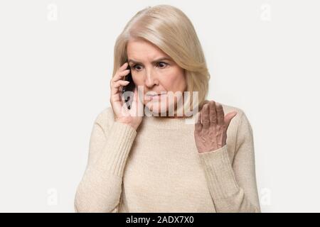 Colpo di Testa di infastiditi vecchia donna avente argomento parlando tramite smartphone Foto Stock