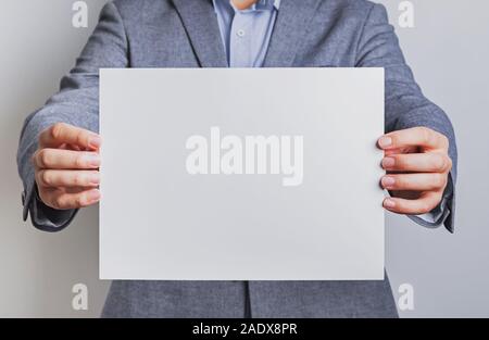 Uomo in tuta in possesso di una carta bianca Foto Stock