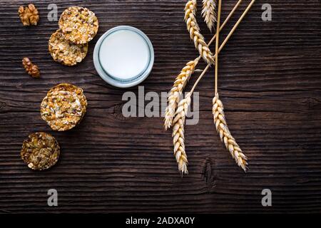 I cookie di cereali con uvetta e nocciole. Una sana alimentazione cibo vegan con la proteina. Vaso con il latte. Foto Stock
