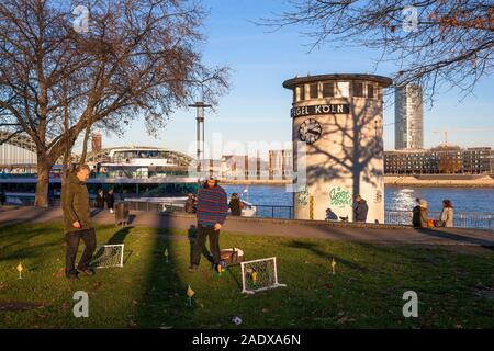 Il livello di acqua orologio del fiume Reno, vista della Torre di triangolo nel quartiere Deutz, uomini kicket giocando a calcio, Colonia, Germania. Un Pegeluhr Foto Stock