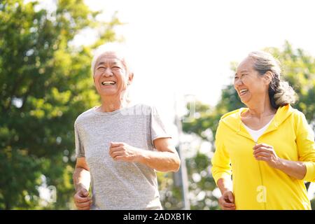 Felice asian coppia senior in esecuzione esercizio all'aperto nel parco Foto Stock