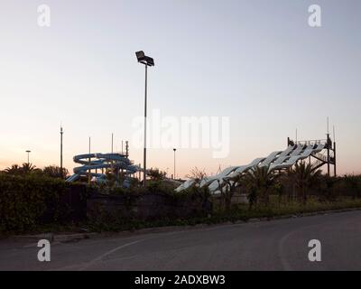 Piscina pubblica con scivoli ad acqua al tramonto Foto Stock