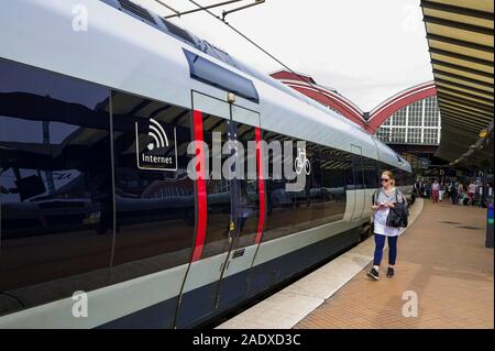 Un viaggiatore femmina a salire su un treno alla Stazione Centrale di Copenhagen, Copenhagen, Danimarca Foto Stock