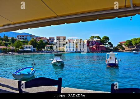 Una splendida vista dal café attraverso il pittoresco porto di grazioso villaggio di pescatori di Assos. Barche nel porto e acque cristalline. Foto Stock