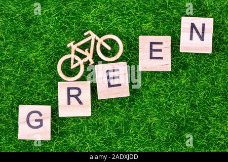 Eco concetto di trasporto con bici di legno e la parola scritta verde in legno lettere prevista sull'erba Foto Stock