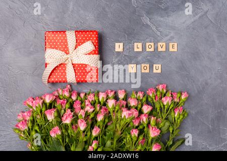 Rosa Rose spray, dono casella rossa e ti amo testo su sfondo grigio. Festa della donna madre il giorno di San Valentino concetto Foto Stock