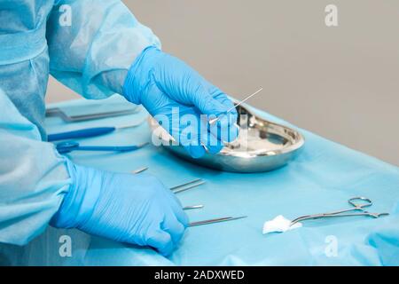 Medico di mano uno strumento di contenimento in sala operatoria. Strumenti per Chirurgia in scatola sterile. Medicina e chirurgia concetto. Foto Stock