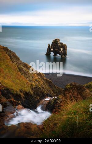 Basalto Hvitserkur pila con una piccola cascata in primo piano nel nord dell'Islanda. Hvitserkur è una spettacolare rock in una forma di un drago o dinos Foto Stock