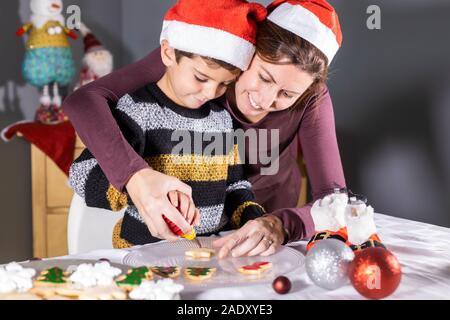 Madre e figlio decotating cookie sul tempo di Natale Foto Stock