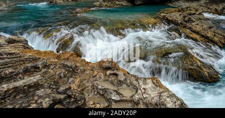 Il Fiume Kicking Horse fluisce giù dalle montagne, divenne una cascata prima di passare sotto un ponte naturale, Parco Nazionale di Yoho, British Columbi Foto Stock