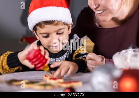 Madre e figlio decotating cookie sul tempo di Natale Foto Stock