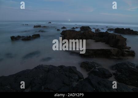 Una lunga esposizione prese dell'oceano per creare un effetto nebbia di le onde attraverso le rocce. Prese a Jeffrey's Bay in Sud Africa Foto Stock