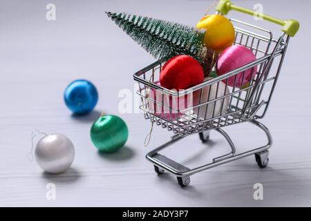 Carrello della spesa e colorato nuovo anno palle su sfondo bianco, l'albero di Natale, piatto shopping laici, orientamento orizzontale Foto Stock