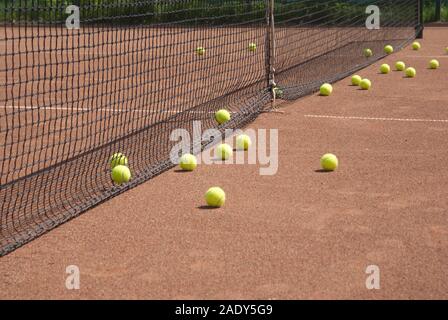 Campo da tennis e molti giallo palla prima di net vista laterale Foto Stock