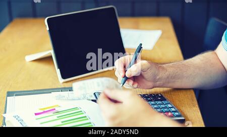 Primo piano delle mani dell uomo il calcolo tasse e il profitto di small business start-up Foto Stock