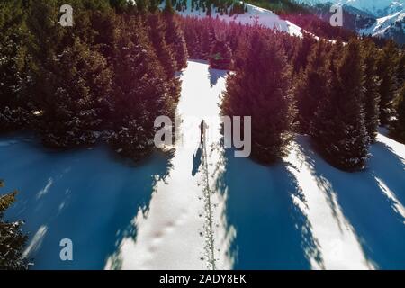 Un giovane uomo viaggi nelle montagne innevate in inverno con gli sci. Tour di sci. Vista aerea Foto Stock