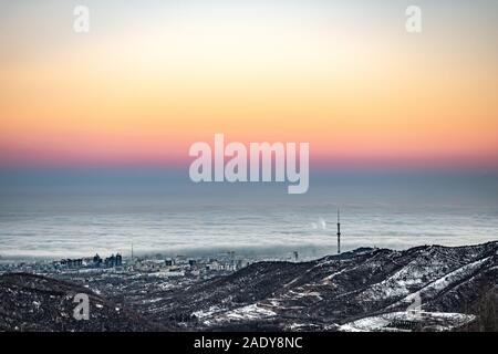 Inizio inverno mattina, nebbia e smog della città di Almaty, Kazakhstan. Affascinante la vista dalle altezze dei monti per la città di inverno Foto Stock