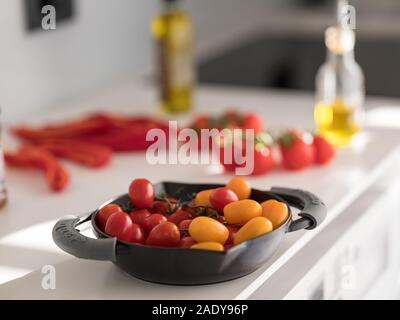 Il giallo e il rosso dei pomodori in un rustico nero in acciaio Vaschetta sul bancone della cucina top vicino fino ad altissima definizione Foto Stock