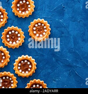 I cookie con caramello sul trendy di colore blu 2020 textured background. Vista superiore piatta o laici. Colore del 2020 sullo sfondo di cibo e di concetto con copia spazio. Square Foto Stock