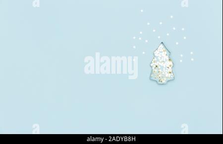Albero di Natale fatto con lo stampo per i biscotti e argento scintillanti stelle su sfondo blu. Lay piatto. Vacanze e concetto di inverno Foto Stock