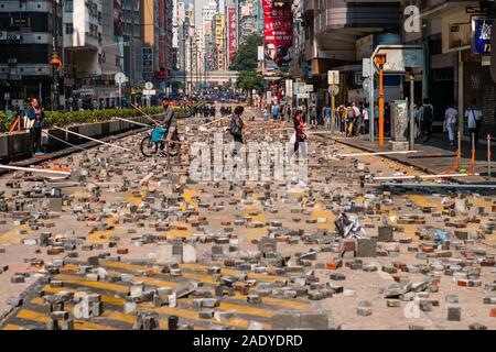 HongKong - Novembre18, 2019: pedoni che attraversano barricati Nathan Road mentre la polizia e protester scontro in background durante il 2019 HongKong proteste Foto Stock