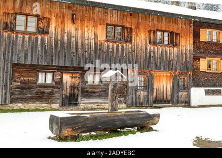 Vecchio tradizionale casa in legno con acqua potabile ben e neve Foto Stock