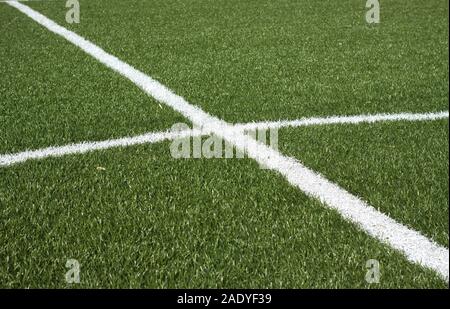 La parte centrale di un campo di calcio con verde erba sintetica e linee bianche su di esso closeup Foto Stock