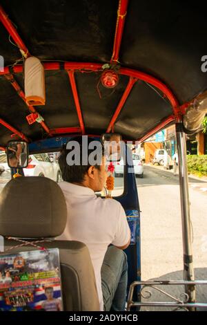 Un uomo alla guida di un rosso tuk tuk per le strade della città di Chiang Mai in Thailandia Foto Stock