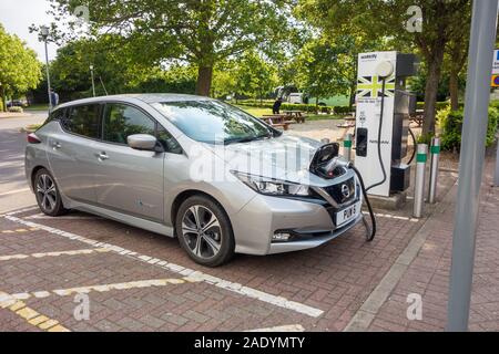 La Nissan Leaf auto elettrica essendo ricaricata presso il punto di ricarica a Warwick alla stazione di servizio sulla M 40 in autostrada in Inghilterra, Regno Unito Foto Stock