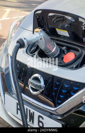 La Nissan Leaf auto elettrica essendo ricaricata presso il punto di ricarica a Warwick alla stazione di servizio sulla M 40 in autostrada in Inghilterra, Regno Unito Foto Stock