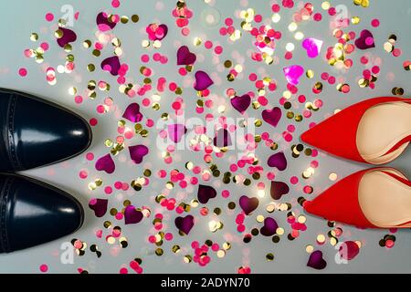 Il giorno di San Valentino con il concetto di uomo e di donna scarpe e colorati coriandoli. Partito, moda. Vista dall'alto. Copia spazio per il testo. Foto Stock