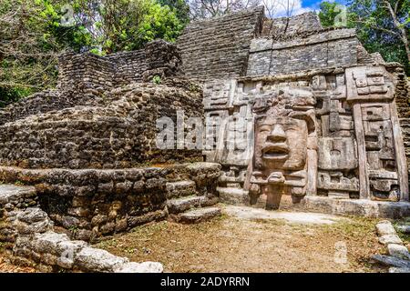 Vecchia pietra antichi Maya di civiltà precolombiane piramide con volto scolpito ed ornamento nascoste nella foresta, Lamanai sito archeologico, Orange Walk Foto Stock