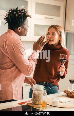 Felice donna ridere dopo l uomo di mettere la farina sul naso Foto Stock