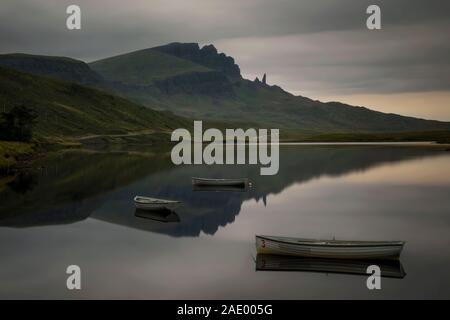 Il vecchio uomo di Storr riflessione in Loch Fada con tre barche, Skye, Scozia Foto Stock