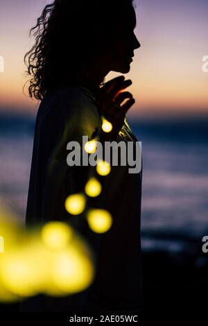 Vita Romantica concetto con lady permanente e il giallo della lampadina luce di romance - defocalizzata naturale all'aperto con sfondo colorato tramonto in bokeh di fondo Foto Stock