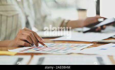 Close-up creative graphic designer con il suo lavoro su selezione a colori su carta a colori. Foto Stock