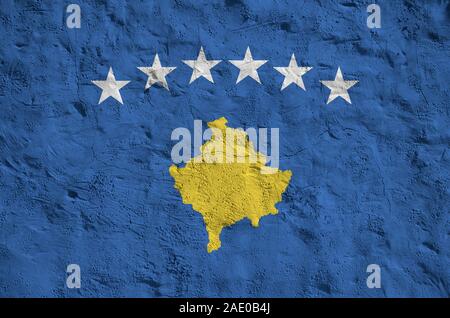 Bandiera del Kosovo raffigurato in luminosi colori di vernice su vecchi intonaci a rilievo parete vicino. Textured banner su sfondo irregolare Foto Stock