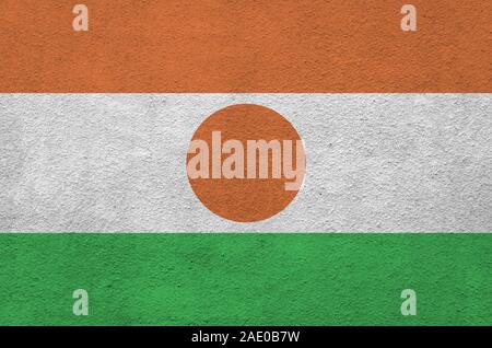 Niger bandiera rappresentata in luminosi colori di vernice su vecchi intonaci a rilievo parete vicino. Textured banner su sfondo irregolare Foto Stock