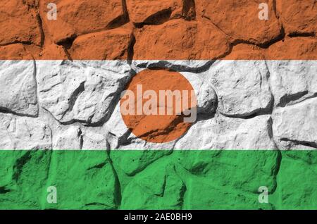 Niger bandiera raffigurata in colori di vernice su un vecchio muro di pietra vicino. Textured banner sulla parete di roccia sullo sfondo Foto Stock