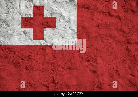 Tonga bandiera rappresentata in luminosi colori di vernice su vecchi intonaci a rilievo parete vicino. Textured banner su sfondo irregolare Foto Stock