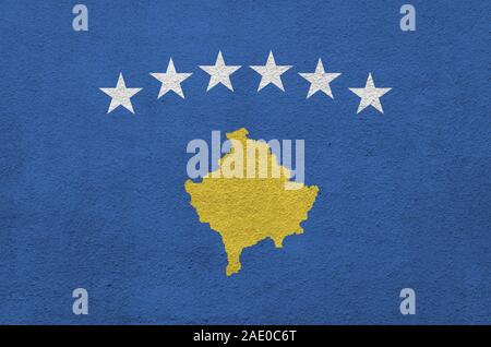 Bandiera del Kosovo raffigurato in luminosi colori di vernice su vecchi intonaci a rilievo parete vicino. Textured banner su sfondo irregolare Foto Stock