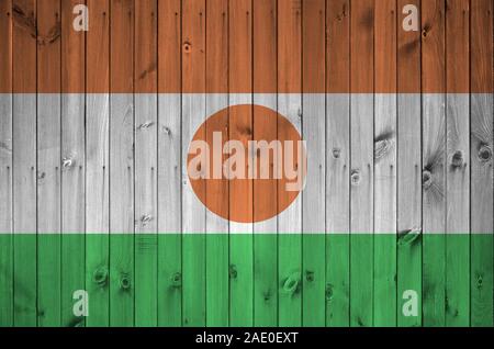 Niger bandiera rappresentata in luminosi colori di vernice sul vecchio muro di legno vicino. Textured banner su sfondo irregolare Foto Stock