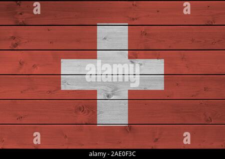 Bandiera della Svizzera rappresentata in luminosi colori di vernice sul vecchio muro di legno vicino. Textured banner su sfondo irregolare Foto Stock