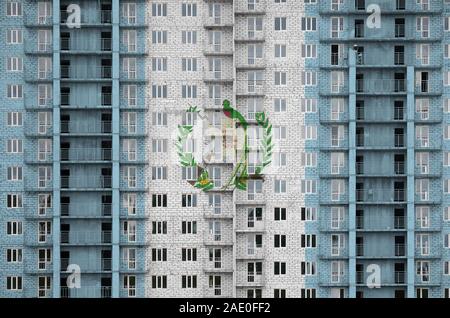 Bandiera del Guatemala raffigurato in colori di vernice su più piani edificio residenziale in costruzione. Textured banner sul grande muro di mattoni in background Foto Stock