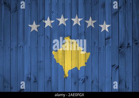 Bandiera del Kosovo raffigurato in luminosi colori di vernice sul vecchio muro di legno vicino. Textured banner su sfondo irregolare Foto Stock