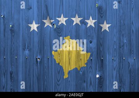 Bandiera del Kosovo raffigurato in luminosi colori di vernice sul vecchio muro di legno vicino. Textured banner su sfondo irregolare Foto Stock