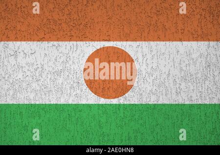 Niger bandiera rappresentata in luminosi colori di vernice su vecchi intonaci a rilievo parete vicino. Textured banner su sfondo irregolare Foto Stock